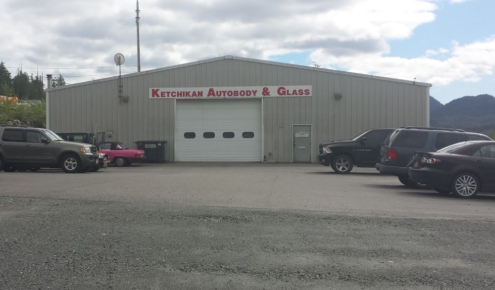 Ketchikan Autobody & Glass building with its red sign and the mountains behind